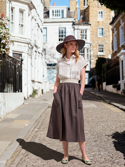 Frau in Rock und bluse mit großem Sonnenhut